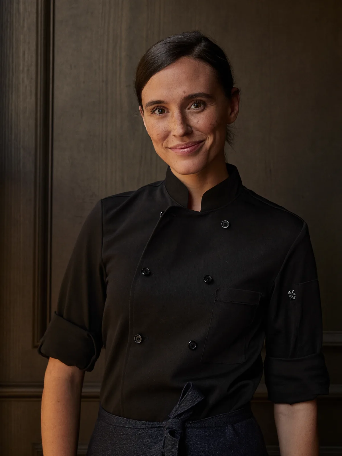 Porträt von Noa Lindqvist, Chef Pâtissière, vor dunkler Eichenvertäfelung